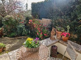 A garden with a table, chair, and flower pots at Little Sea Thrift in Lyme Regis