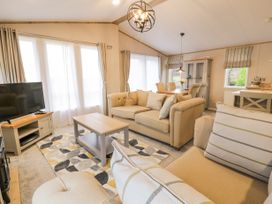 A living room with sofas coffee table television and dining table at Debonair Lodge in Three Lochs Holiday Park near Glenluce