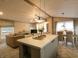 An open plan living room and dining area with a kitchen island and flowers at Debonair Lodge in Three Lochs Holiday Park near Glenluce