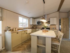 A kitchen with a marble island countertop and two chairs at Debonair Lodge in Three Lochs Holiday Park near Glenluce
