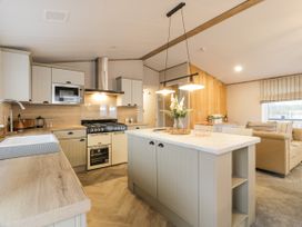 A kitchen with an island counter range oven microwave and a living area with a sofa at Debonair Lodge in Three Lochs Holiday Park near Glenluce