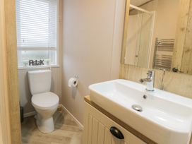 A bathroom with a toilet a sink a mirror and a window with blinds at Debonair Lodge in Three Lochs Holiday Park near Glenluce