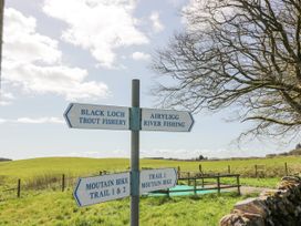 A signpost with directions to Black Loch trout fishery Airyligg river fishing and mountain bike trails in a grassy field with trees at Debonair Lodge in Three Lochs Holiday Park near Glenluce