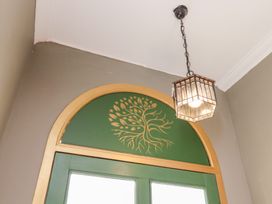 A green door with a decorative tree design and light fixture at Rutland Grange in Filey