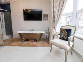 A bathroom with a bathtub and television at Rutland Grange in Filey