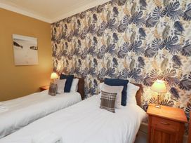 A bedroom with two beds and a picture on the wall at Rutland Grange in Filey