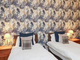 A bedroom with two beds and a large floral wallpaper at Rutland Grange in Filey