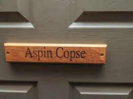 A wooden nameplate labeled Aspin Copse on a door