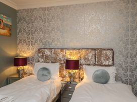 A bedroom with two single beds and bedside lamps at Rutland Grange in Filey
