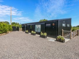 A house with a gravel driveway and planters at Y Cwt Moelfre