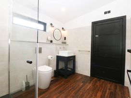 A bathroom with a shower, sink, and toilet at Y Cwt in Moelfre