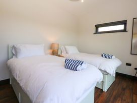 A bedroom with two beds and a lamp at Y Cwt in Moelfre