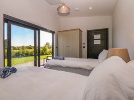 A bedroom with two beds and a wardrobe at Y Cwt in Moelfre