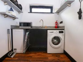 A laundry room with a washing machine and microwave at Y Cwt, Moelfre