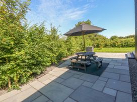 A garden with a table and bench under an umbrella at Y Cwt Moelfre