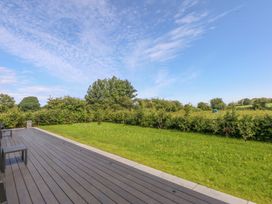 A garden with decking and grass at Y Cwt in Moelfre