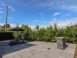 A garden with a picnic table and umbrella at Y Cwt in Moelfre