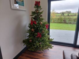 A Christmas tree with decorations and a view outside at Y Cwt in Moelfre