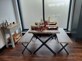 A dining room with a table and benches at Y Cwt in Moelfre
