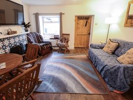 A living room with wooden chairs a sofa a patterned rug and a wooden door at 3 Victoria Cottages in Heacham