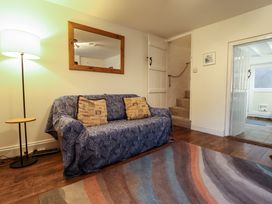 A living room with a covered sofa and two cushions a floor lamp and a mirror on the wall at 3 Victoria Cottages in Heacham
