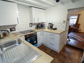 A kitchen with white cabinets wooden countertops a stainless steel sink a microwave and an espresso machine at 3 Victoria Cottages Heacham