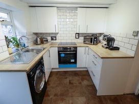 A kitchen with white cabinets and appliances including a sink oven washing machine microwave and coffee machine at 3 Victoria Cottages Heacham