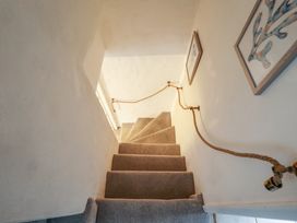 A narrow carpeted staircase with a rope handrail and framed pictures on the wall at 3 Victoria Cottages in Heacham
