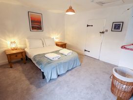A bedroom with a double bed with blue blanket and two towels bedside tables with lamps a door and a laundry basket at 3 Victoria Cottages in Heacham