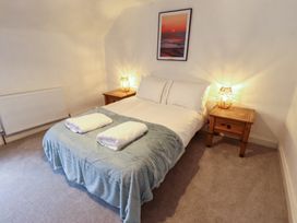 A bedroom with a double bed two bedside tables with lamps and a framed picture above the bed at 3 Victoria Cottages in Heacham
