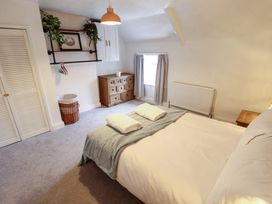 A bedroom with a bed topped with folded towels curtains on a window and wooden furniture at 3 Victoria Cottages in Heacham