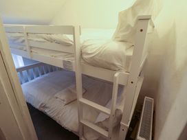 A small bedroom with a white bunk bed and white bedding at 3 Victoria Cottages in Heacham