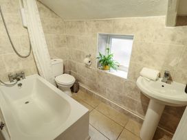 A bathroom with a bathtub toilet sink window with a plant and tiled walls at 3 Victoria Cottages Heacham