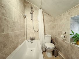 A bathroom with a bathtub shower combination toilet and a small plant on a tiled wall at 3 Victoria Cottages in Heacham