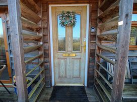A wooden front door with a wreath on it and a black doormat on a wooden porch at Hillview in Stottesdon near Cleobury Mortimer