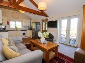 A living room with a grey sofa and wooden coffee table next to a kitchen area with white cabinets and a washing machine at Hillview in Stottesdon near Cleobury Mortimer
