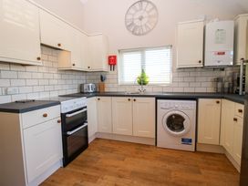 A kitchen with white cabinets a black countertop a washing machine an oven a toaster a sink and a clock on the wall at Hillview in Stottesdon near Cleobury Mortimer