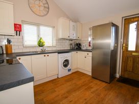A kitchen with white cabinets a washing machine a stainless steel fridge and a wooden door at Hillview in Stottesdon near Cleobury Mortimer