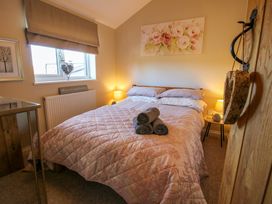 A bedroom with a double bed with a quilt and towels on top a bedside table with a lamp and a window with a blind at Hillview in Stottesdon near Cleobury Mortimer