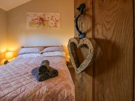 A bedroom with a bed covered by a quilt and rolled towels on top with a lamp on a bedside table at Hillview in Stottesdon near Cleobury Mortimer