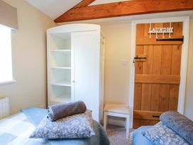 A bedroom with two beds each having a pillow and rolled towel a white wardrobe a wooden door with laundry hooks and a small stool at Hillview in Stottesdon near Cleobury Mortimer