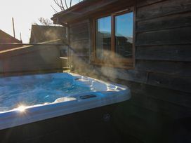 An outdoor hot tub with steam rising near a wooden building with a window at Hillview in Stottesdon near Cleobury Mortimer