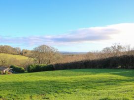 A grassy field with trees and a small building under a blue sky at Hillview in Stottesdon near Cleobury Mortimer