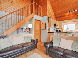 A living room with a staircase and kitchen at Cornish Woodland Retreat Near St Tudy