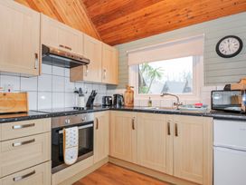 A kitchen with cabinets, a sink, an oven, and a microwave at Cornish Woodland Retreat Near St Tudy