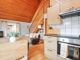A living room with a kitchen and a staircase at Cornish Woodland Retreat Near St Tudy