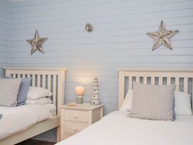 A bedroom with two beds and a nightstand at Cornish Woodland Retreat near St Tudy