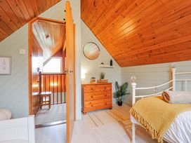 A bedroom with a bed, chest of drawers, and mirror at Cornish Woodland Retreat Near St Tudy