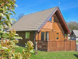 A wooden house with a sloped roof and a deck at Cornish Woodland Retreat near St Tudy