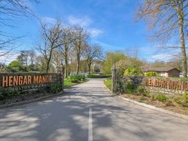 Entrance sign of Hengar Manor Holiday Park with trees and pathway near St Tudy